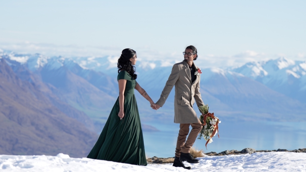 Bride & groom walk across mountain snow